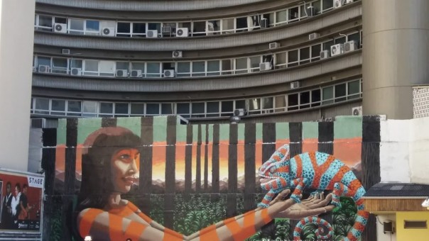 Arte de Rodrigo Rizo em muro de estacionamento no centro de Florianópolis. Ao fundo, detalhe do prédio Ceisa Center, um dos ícones da arquitetura modernista da cidade, projetado pelo arquiteto Moysés Liz. 